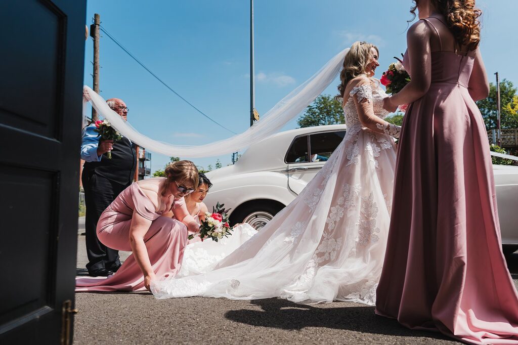 Bride having her veil altered outside the church door way // St Anne's Church, Nantwich