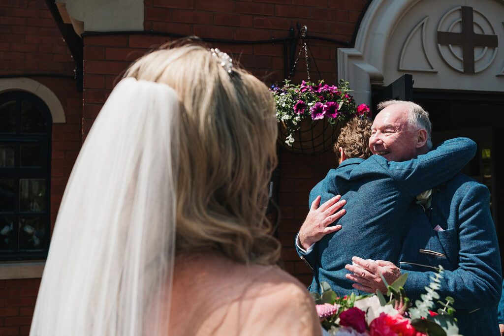Bride's dad hugging the Groom outside the church, St. Anne's Church // Combermere Abbey Wedding Photographer