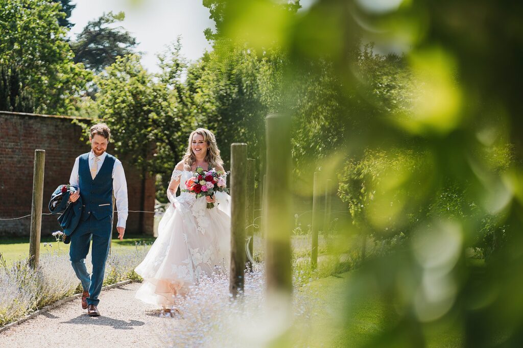 Bride and Groom walking through the maze towards their guests at Combermere Abbey // Wedding Photographer Shropshire