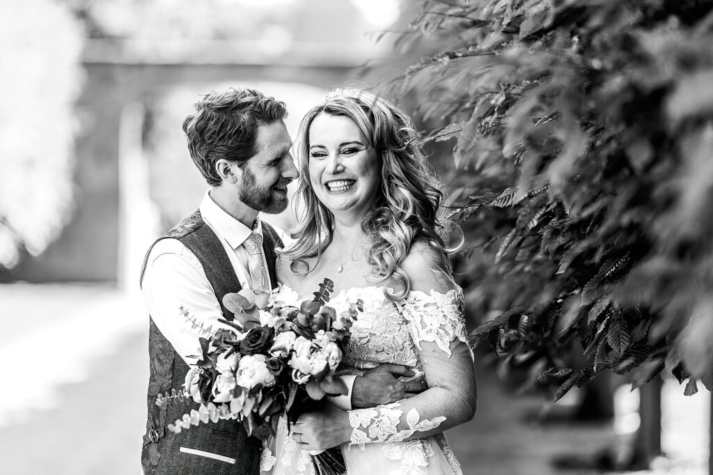 Bride and Groom cuddling with in the trees on the walk way from the cottages at Combermere Abbey // Cheshire Wedding Photographer