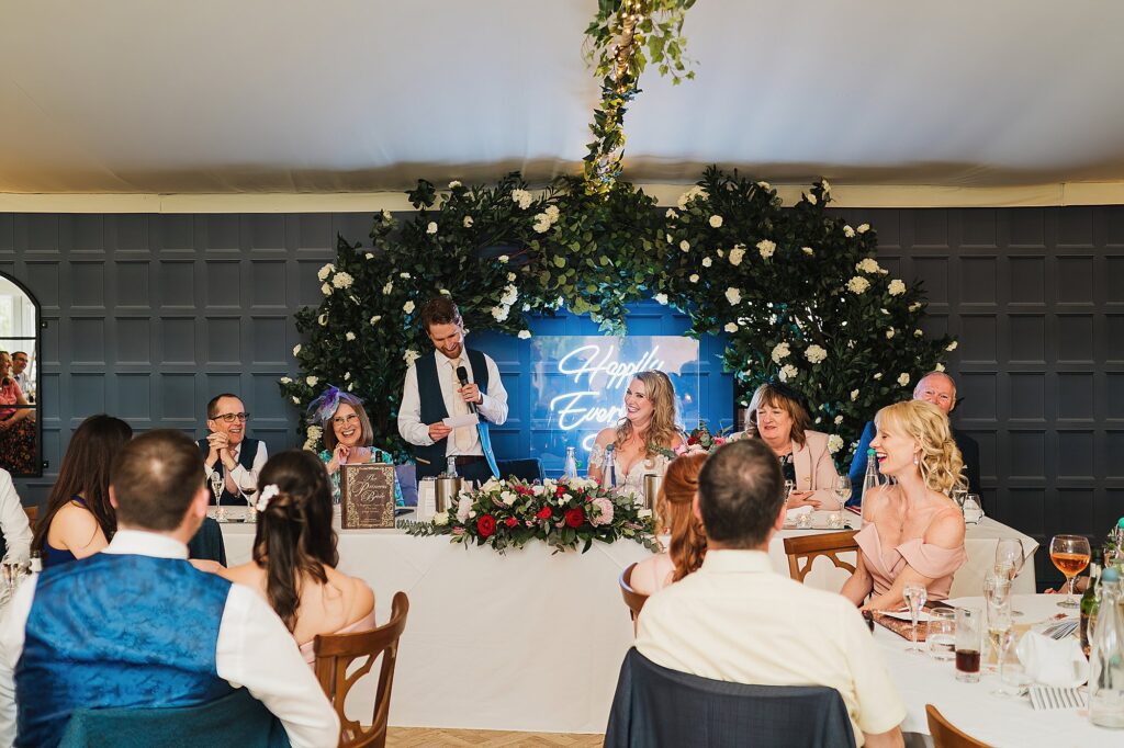 Top table and guests giggling at the groom's speech at Combermere Abbey Cheshire Wedding Photographer