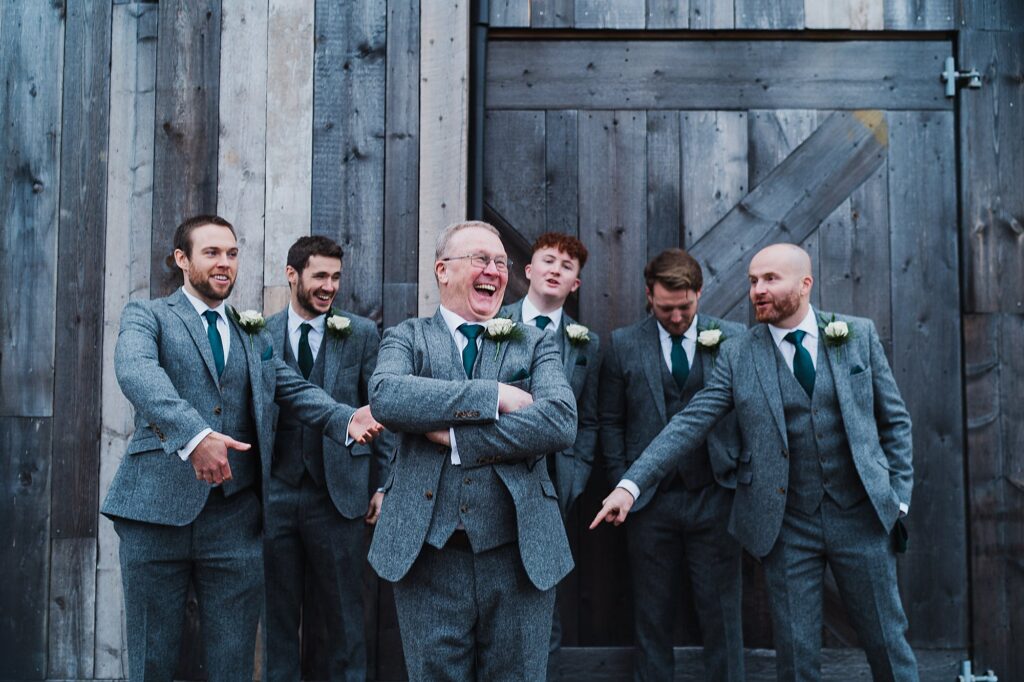 All the groomsmen and father of the groom messing around outside of Grange Barn, the boys pointing their fingers as Father of the Groom photobombed // Cheshire Wedding Venue