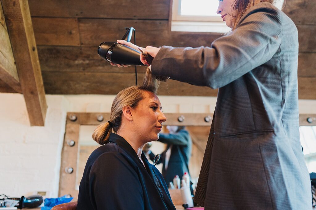 Bride having her hair blow dried in the bridal suite at Grange Barn Wedding Venue