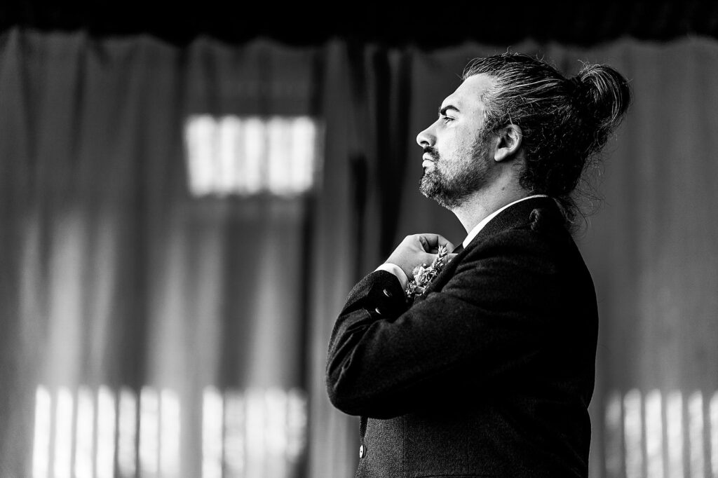 Groom altering his tie while looking out of the window // Cheshire Wedding Photographer