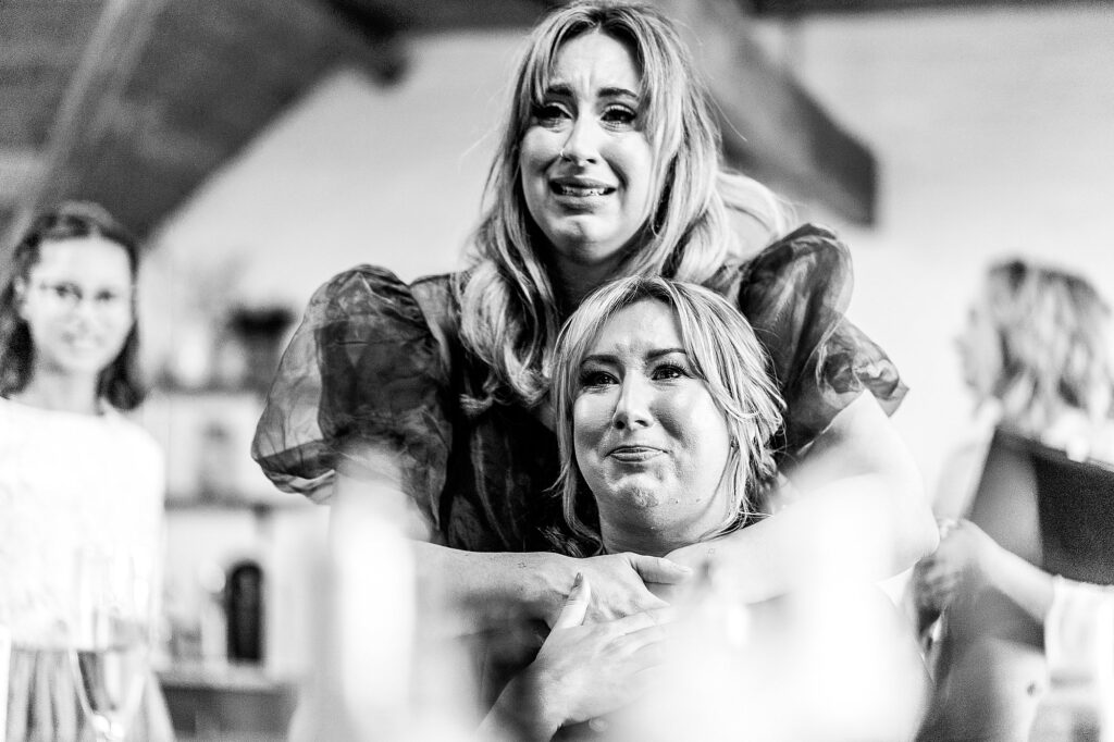 Bride crying in the mirror with her sister cuddling her and crying at the same time // Grange Barn Wedding Photographer