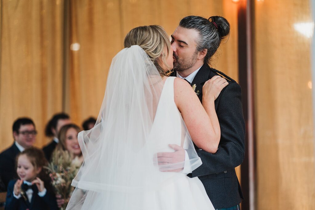 Bride and Groom kissing at the top of the aisle once they are officially married at Grange Barn Wedding Venue Cheshire