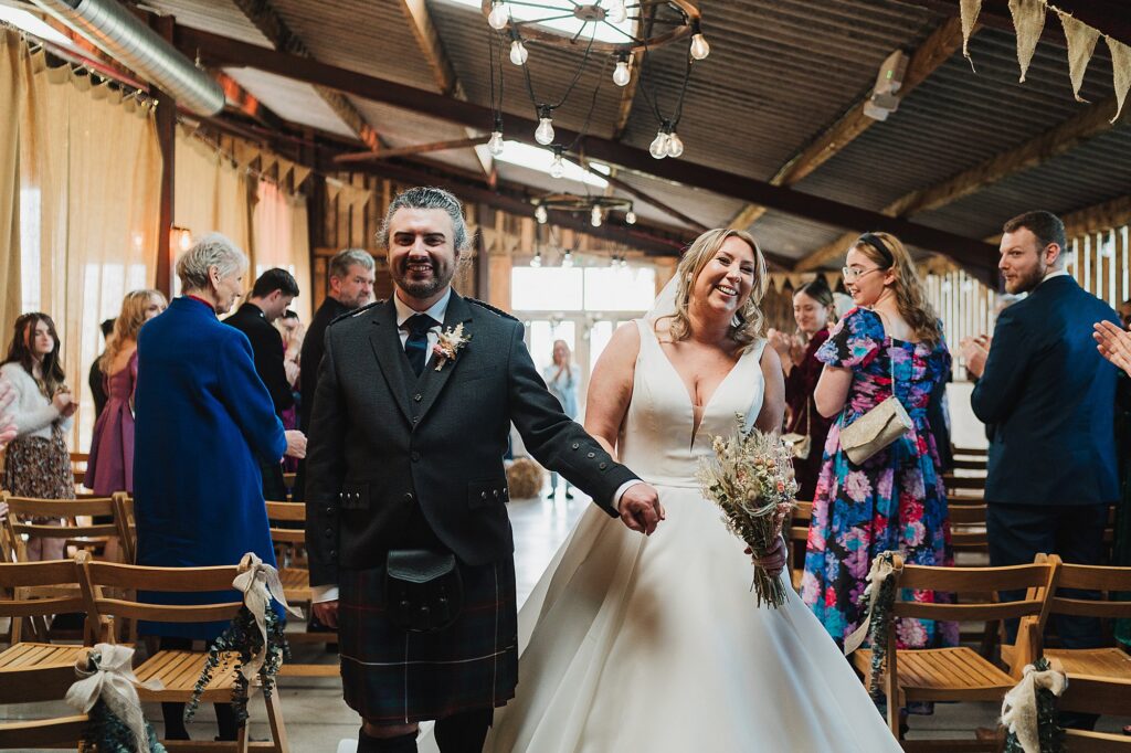 Bride and Groom beaming with the biggest smiles as they come down the aisle together at Grange Barn Wedding Venue // Charlotte Giddings Photography