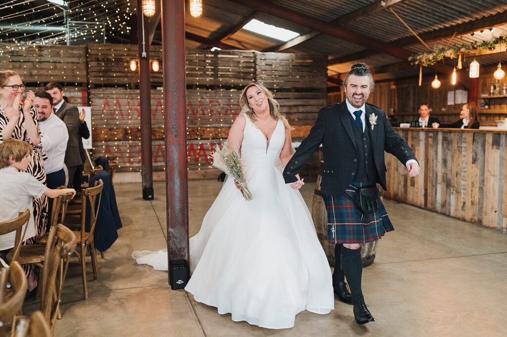 Bride and Groom walking into their wedding breakfast at Grange Barn Wedding Venue, Cheshire