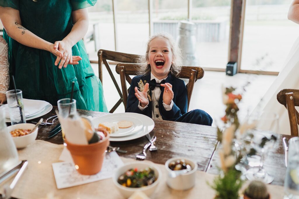 Page Boy laughing his little head off at something funny while he is sat on the top table at Grange Barn Cheshire Wedding Venue