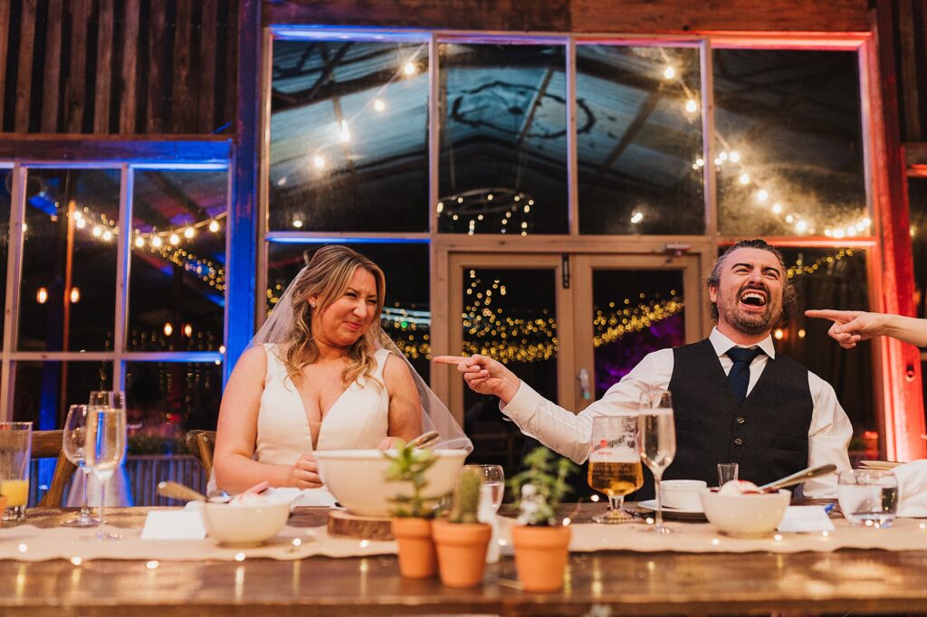 The bride has got the shot of vodka in the polish game, guests and husband laughing as she winces at the taste of the vodka // Charlotte Giddings Photography