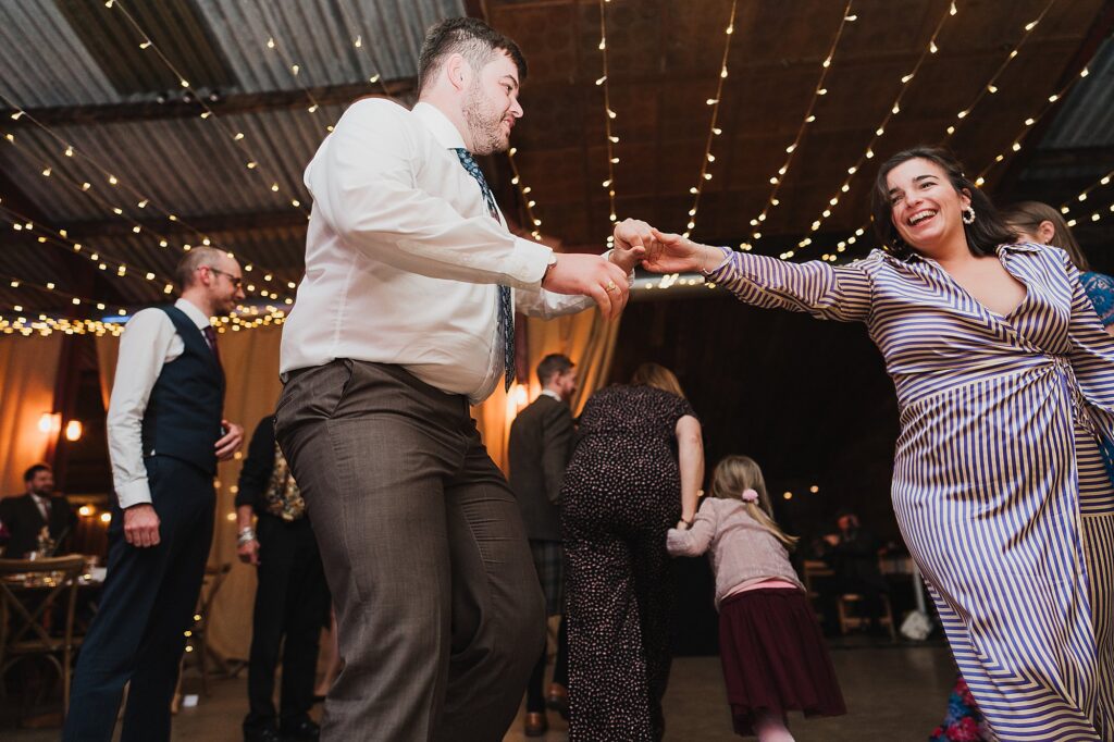 Couple of wedding guests listening to instructions from the Ceilidh Band and starting to dance the night away // Charlotte Giddings Photographer