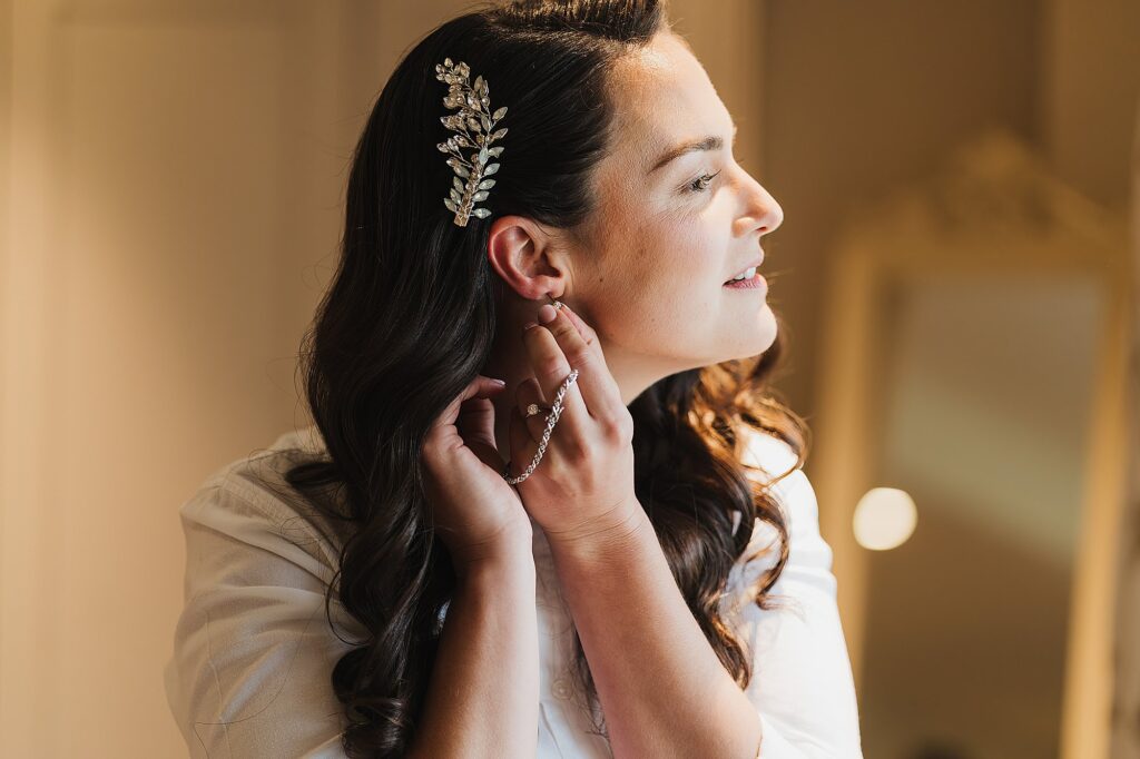 Bride putting on her mother's earrings in the window before she puts her wedding dress on // Charlotte Giddings Photography