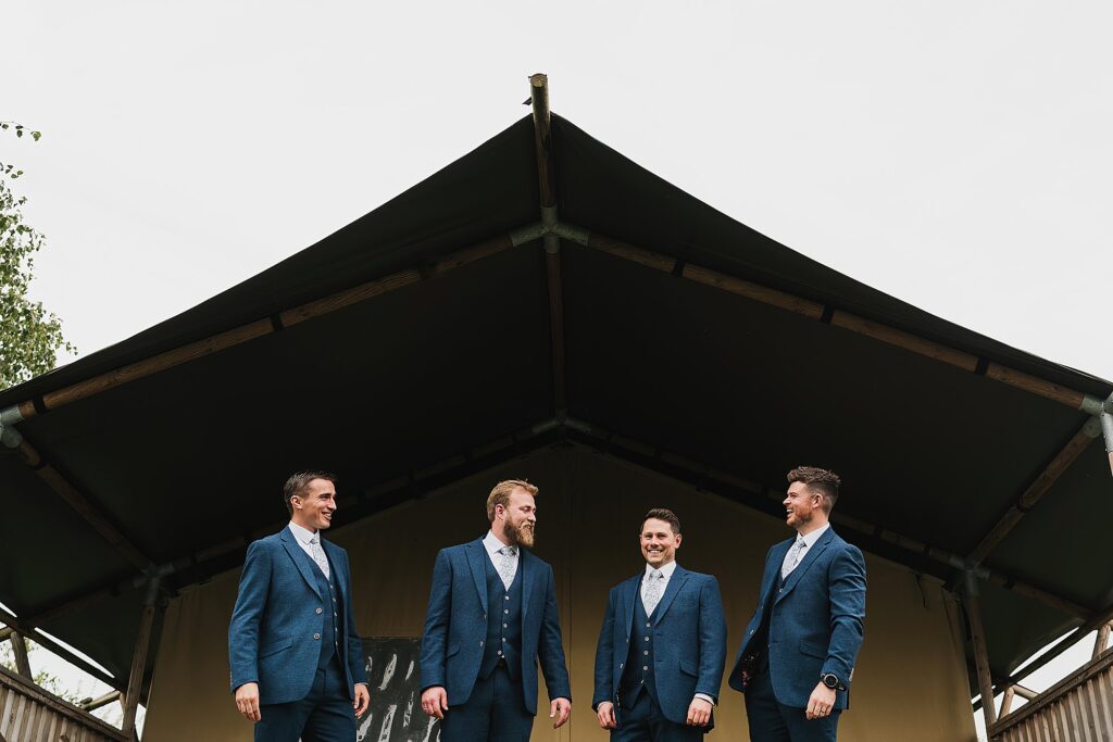Groom and his groomsmen outside the safari tent laughing between each other // Hencote Wedding Photography