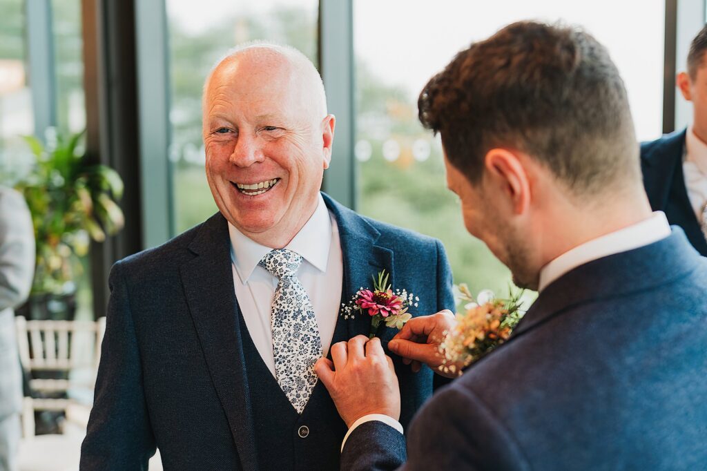 Groom helping his dad apply his button hole on to his jacket // Shrewsbury Wedding Photographer