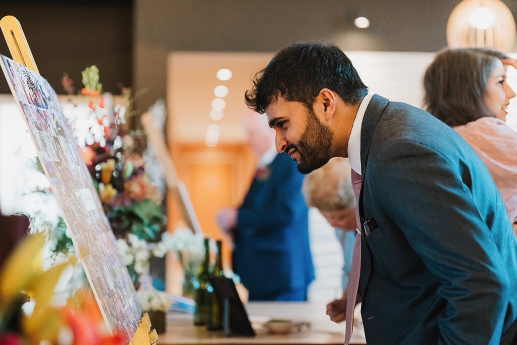 Guest taking the time to look at the photo montage of the couple of all the good times at Hencote Estate Wedding Reception