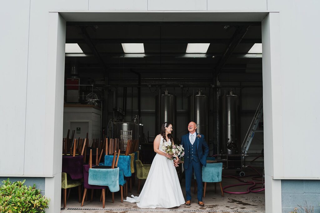 Bride and her dad giggling in the vineyard unit to keep dry at Hencote Estate before she walks down the aisle // Shrewsbury Wedding Photographer