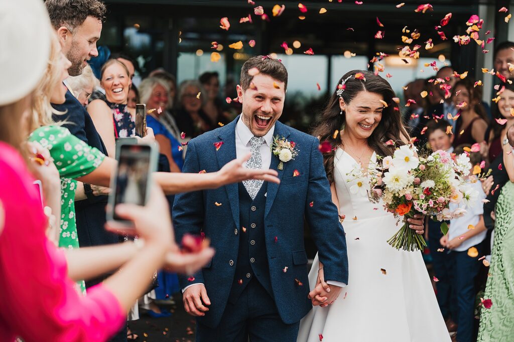 Bride and Groom walking through the guests throwing confetti at Hencote Estate, Shrewsbury