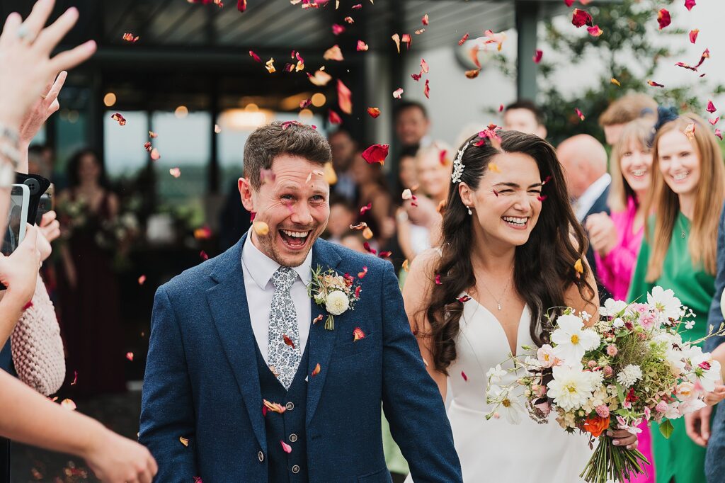 Bride and Groom beaming with smiles as the guests throw confetti over them at Hencote Estate // Shropshire Wedding Photographer