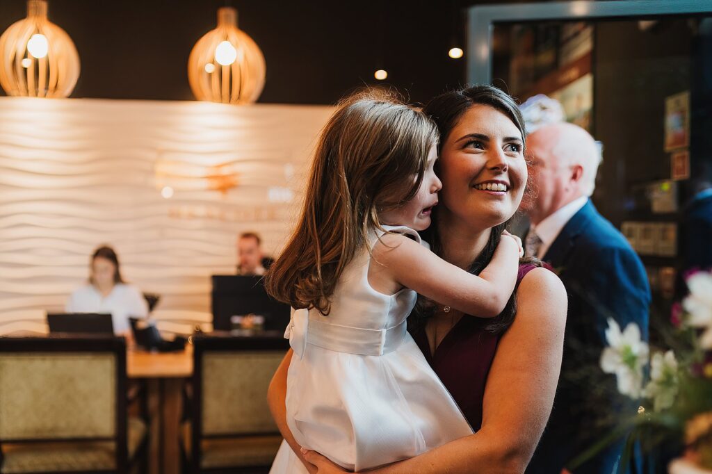 Bride's sister cuddling her emotional daughter as she continues to chat to another wedding guest // Shropshire Wedding Photographer