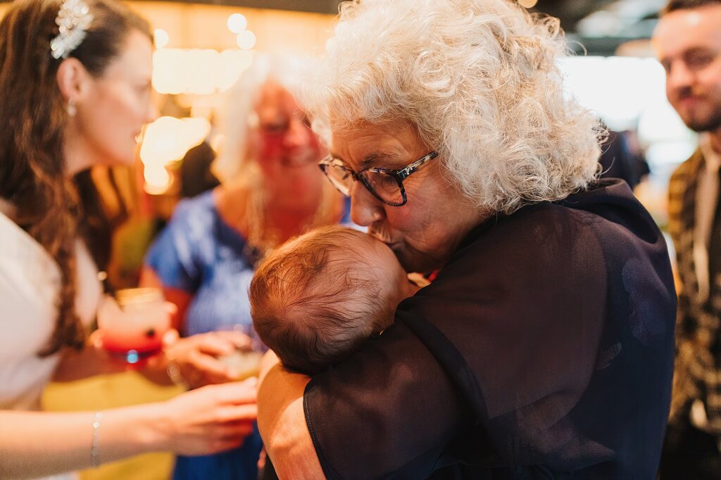 Mother of the Groom having a cuddle with the newest member of the family and kisses him on the head // Wedding Photographer Shropshire