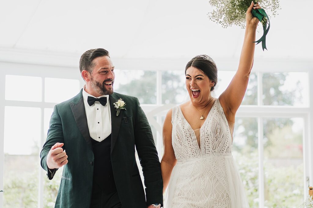 Bride and Groom elated and cheering that they are about to walk down the aisle in the Glasshouse, Combermere Abbey
