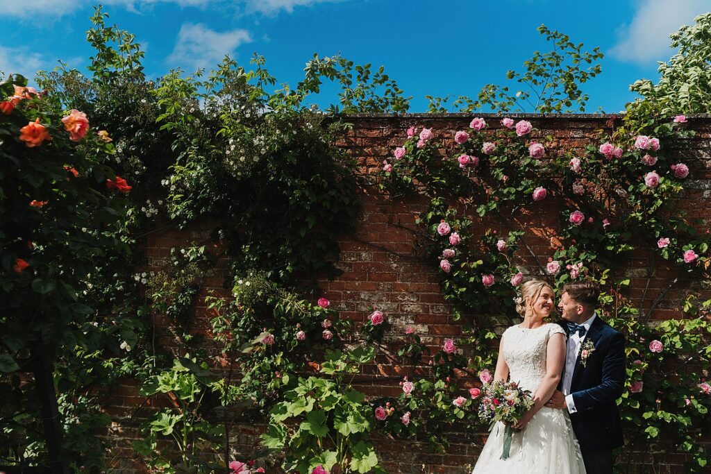 Bride and Groom cuddling and having a moment together in the walled gardens with the roses in June // Summer Wedding Combermere Weddings