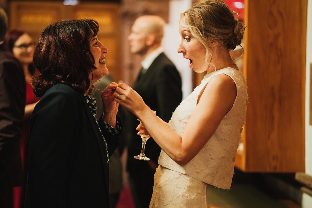 Bride looking shocked at a necklace that a guest is showing her // Chester Town Hall Wedding Photographer