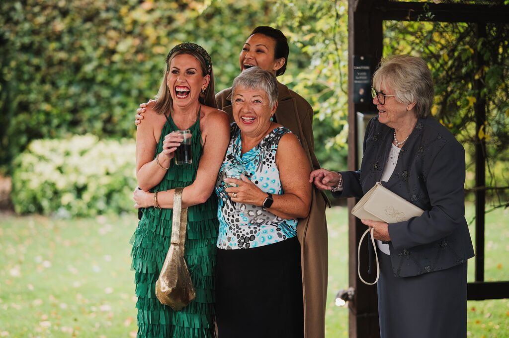 Guests laughing at something in the gardens at Nunsmere Hal // Cheshire Wedding Photography