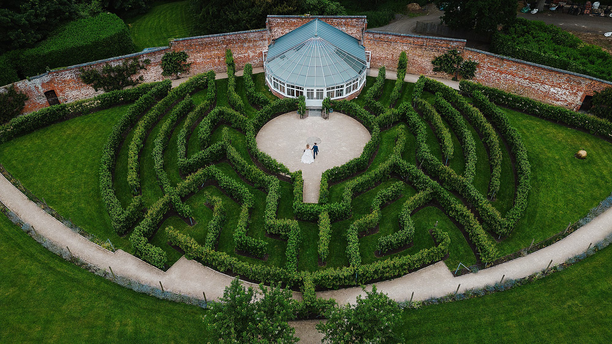 Combermere Abbey Wedding Photographer Cheshire Glasshouse Drone bride and groom walking through the maze at combermere abbey cheshire venue drone shot